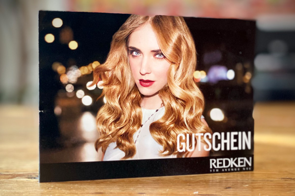 Gutschein von Schramm Haarformer: blonde, langhaarige Frau, verschwommener Hintergrund, eher dunkel gehalten
