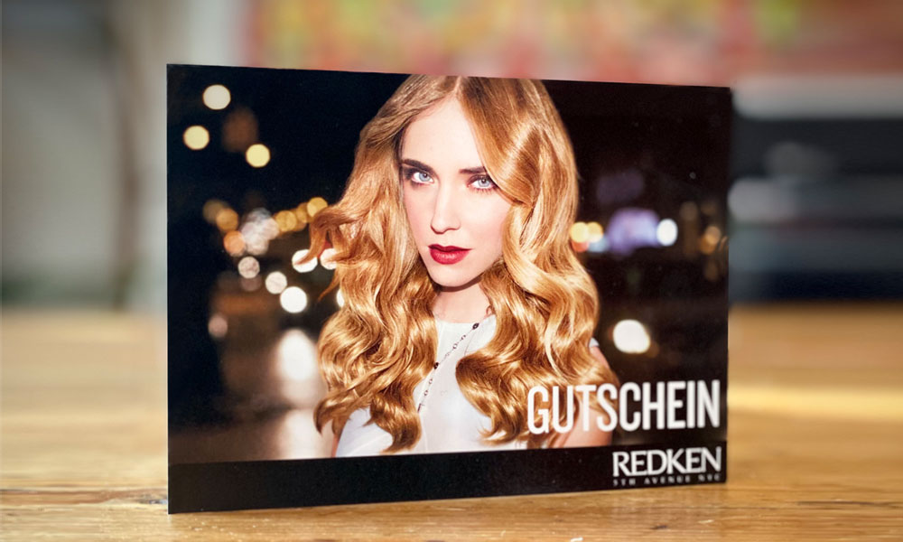 Gutschein von Schramm Haarformer: blonde, langhaarige Frau, verschwommener Hintergrund, eher dunkel gehalten